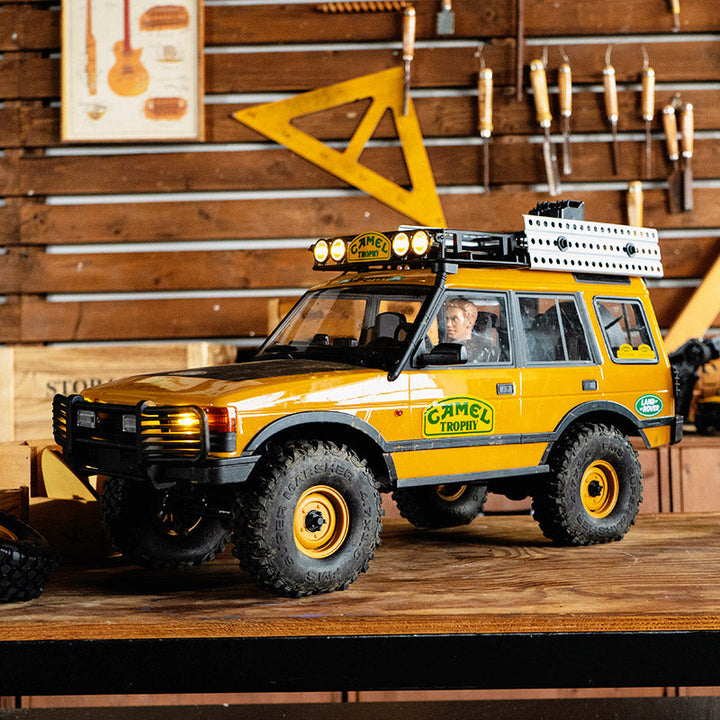 A yellow Camel Trophy Land Rover Discovery RC car with a roof rack
