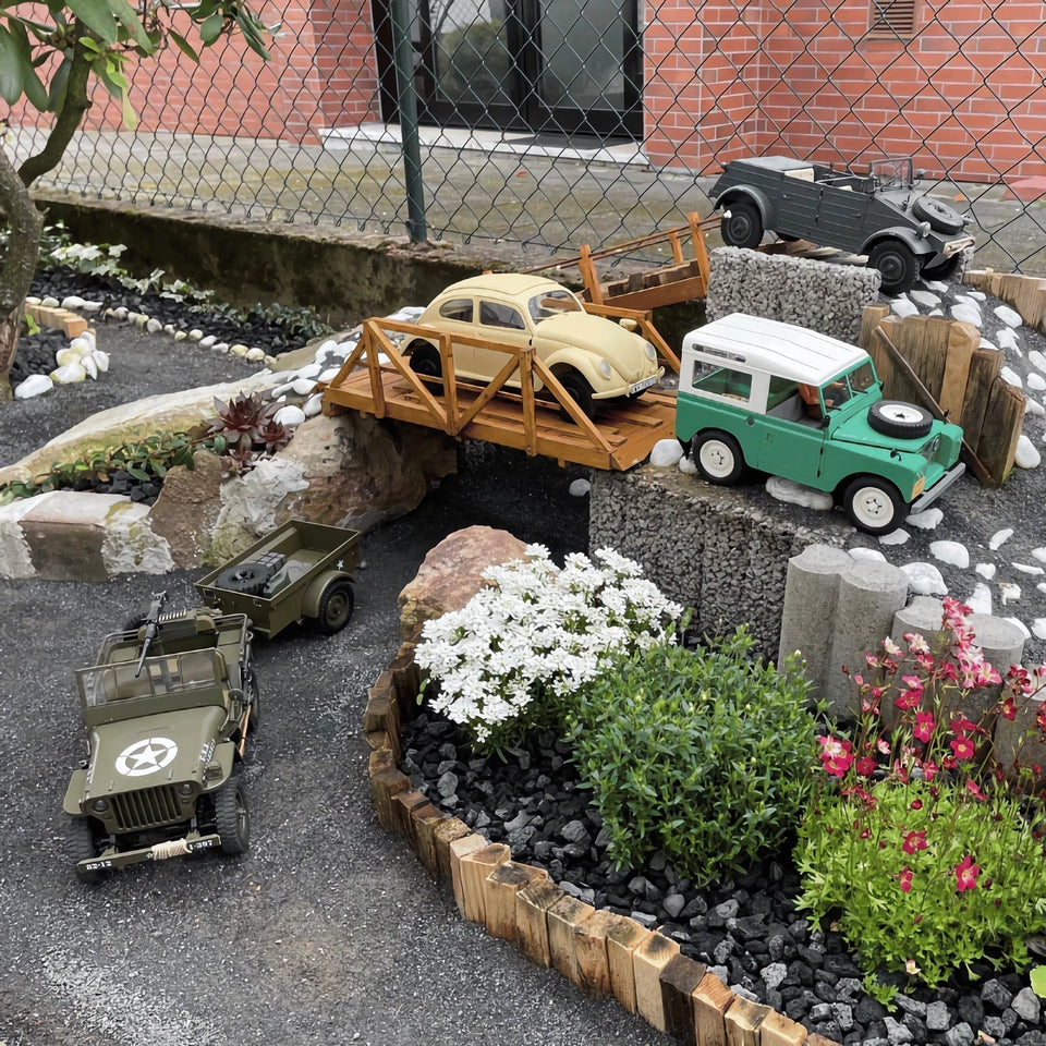 RC crawler models displayed on a miniature outdoor garden rock course.