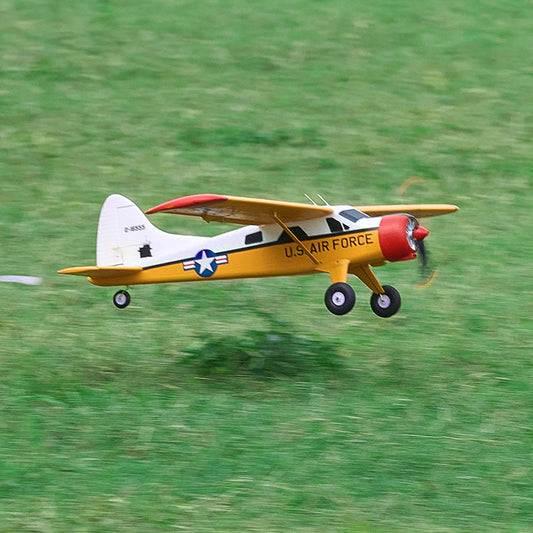 A yellow and white U.S. Air Force style rc trainer plane flying over a grass field, perfect for those searching for the most stable rc plane or a reliable remote control airplane for adults.