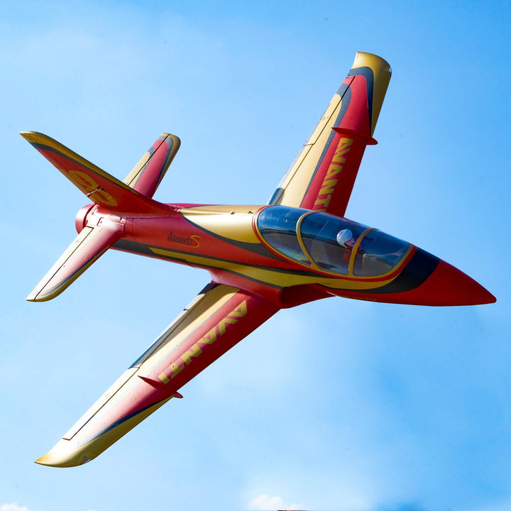 A red and gold jet trainer aircraft flying against a blue sky. The distinctive aircraft features the 'Avant' and 'AvantS' markings on its fuselage.