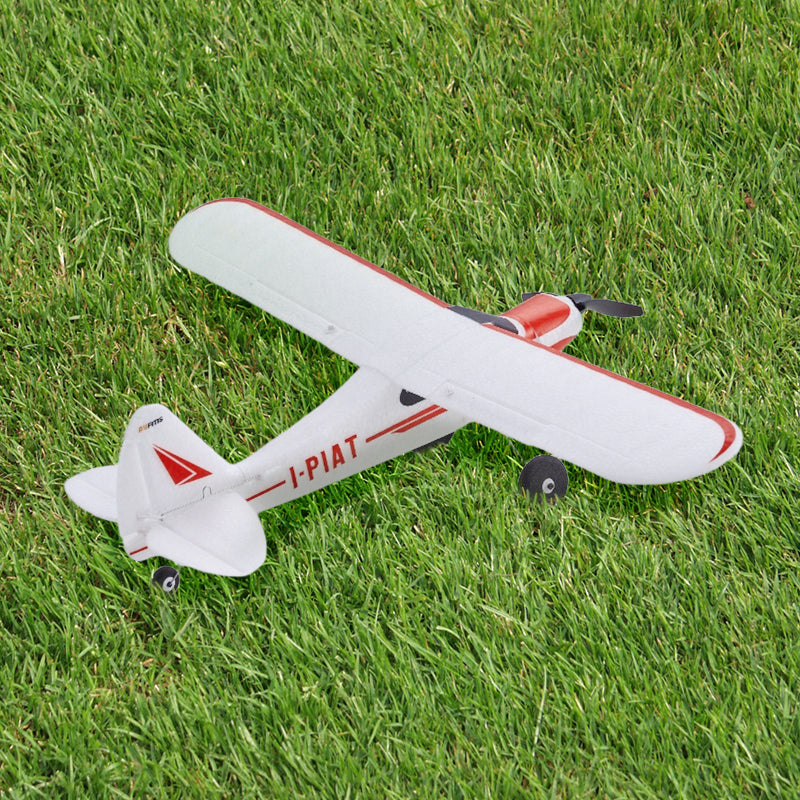 A red and white FMS RC Plane rests on a lush green grass field