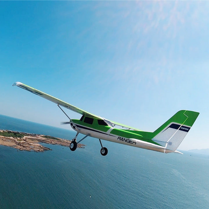 green RC aircraft flying above coastal landscape