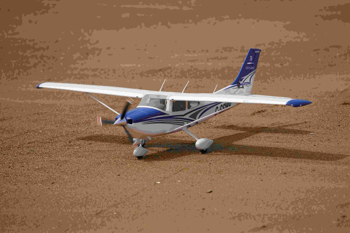 blue and white RC Cessna model on sandy ground