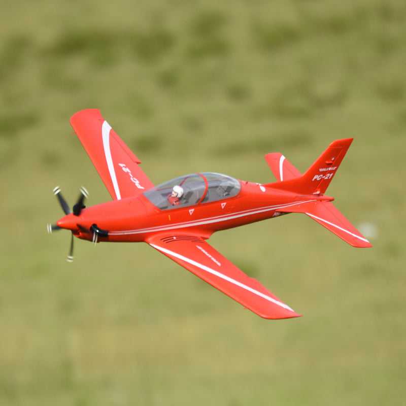 Red FMS 1100mm PC-21 Pilatus PNP model airplane in flight with white accents and 'PC-21' branding.