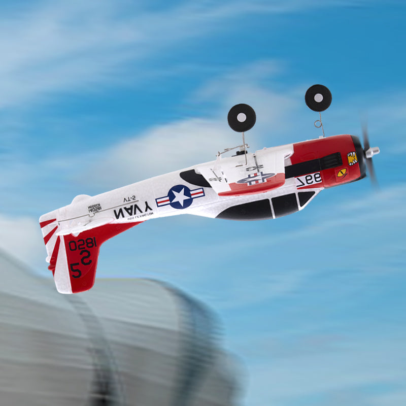 Model airplane with red and white design flying against a blue sky.