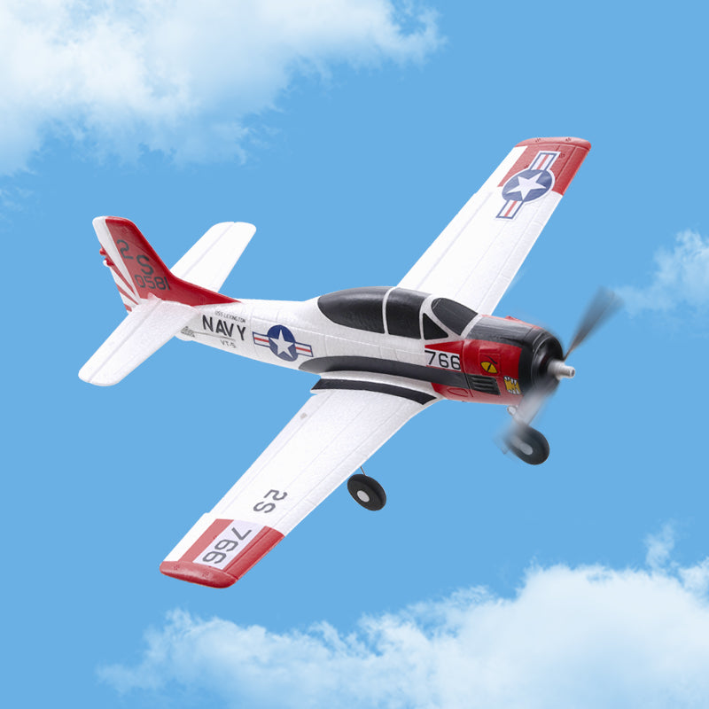 Model airplane with 'Navy' markings flying against a blue sky with clouds