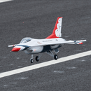 F-16 Thunderbird 64mm EDF jet model flying over a runway in vibrant colors