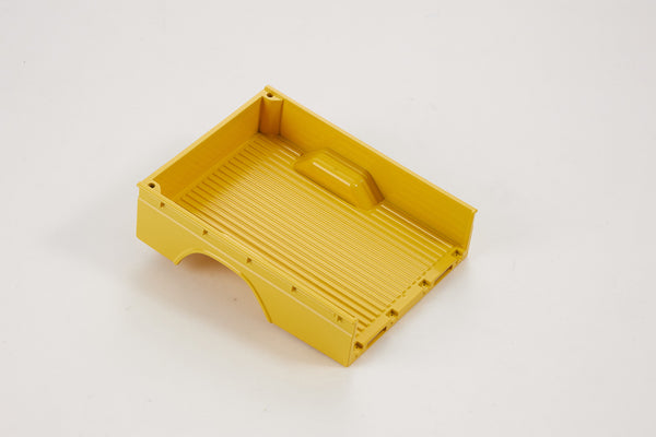 Yellow plastic truck bed part for RC models, featuring ribbed texture.