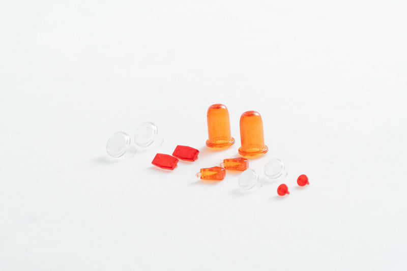 Red and orange RC model light lenses and accessories on a white background.