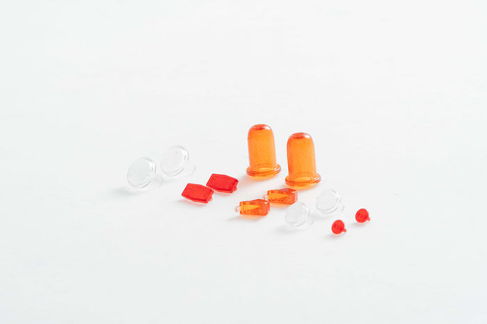 Red and orange RC model light lenses and accessories on a white background.