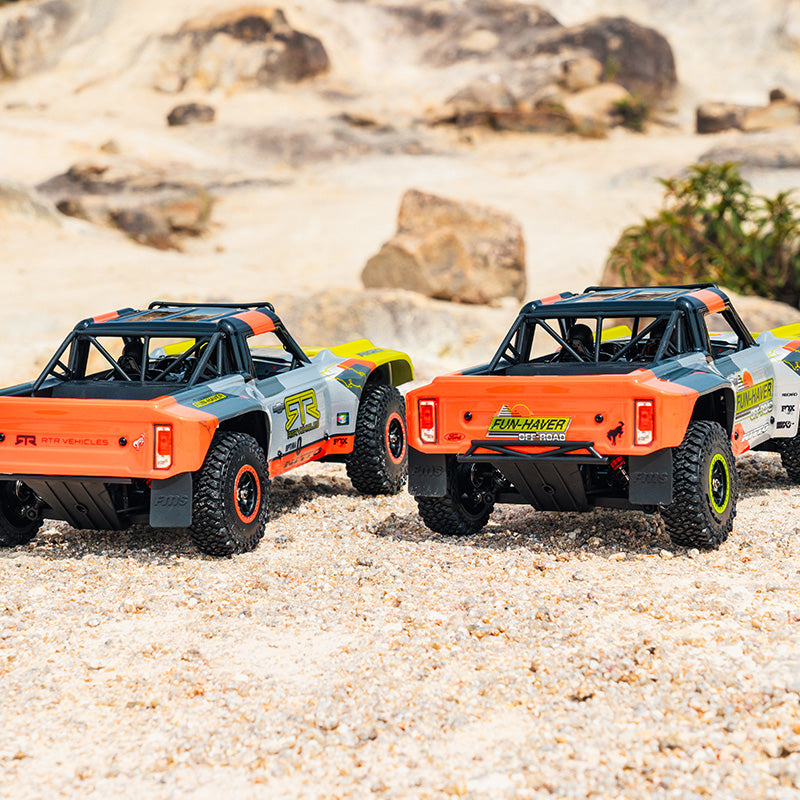 Two FMS 1:18 Ford Bronco RTR RC trucks with orange and grey bodies on sand.