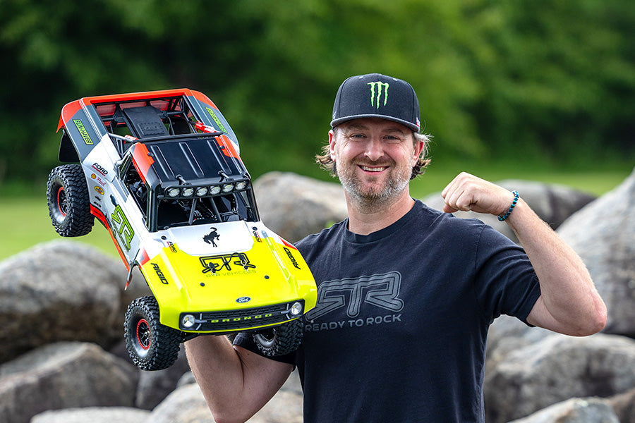 Man holding a toy off-road vehicle with a blurred green background