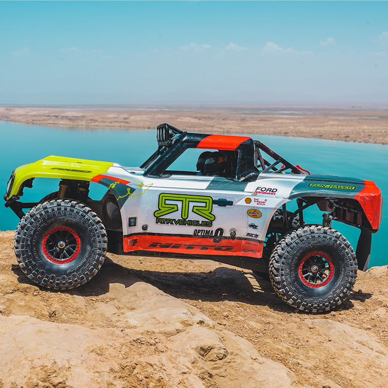 Colorful off-road vehicle on a rocky terrain with a body of water in the background