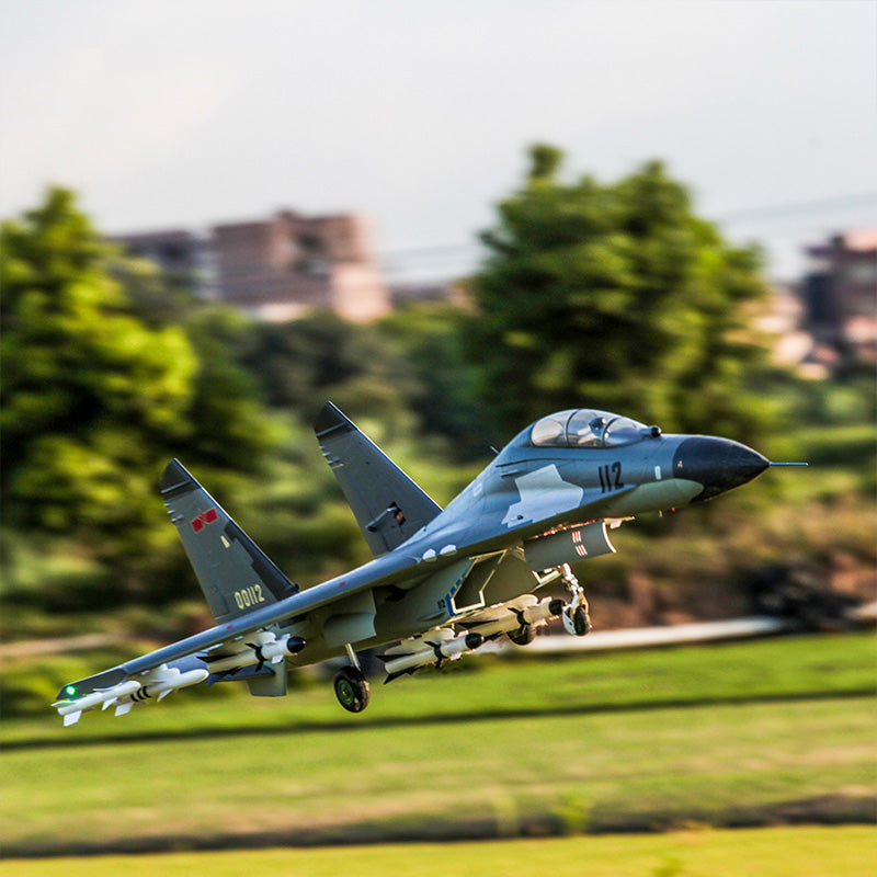 FMS Dual 70mm EDF SU-27/J-11 PNP jet in flight, showcasing camouflage and armament.
