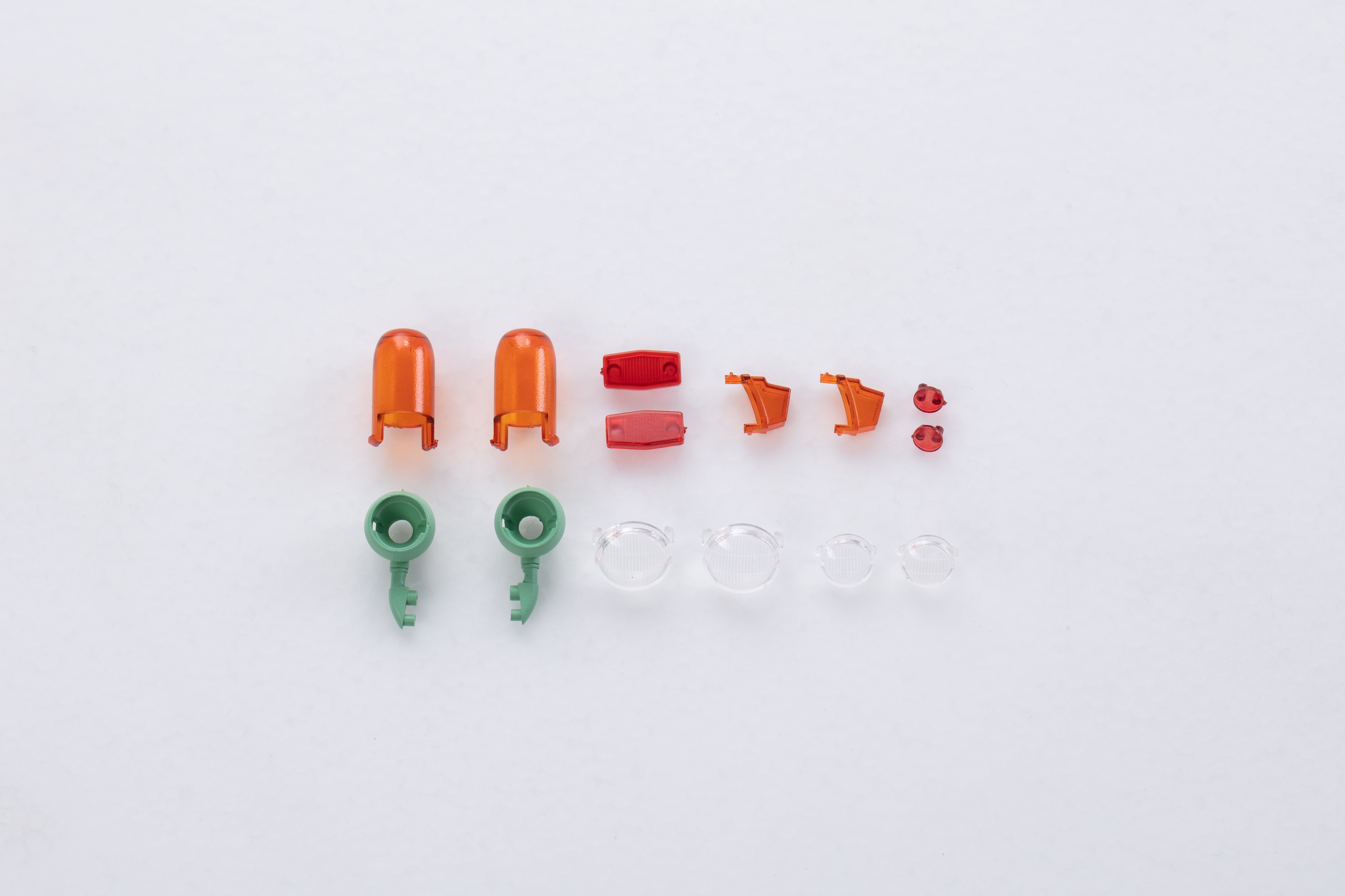 Assorted RC model parts: orange/red body, green clips, transparent lenses