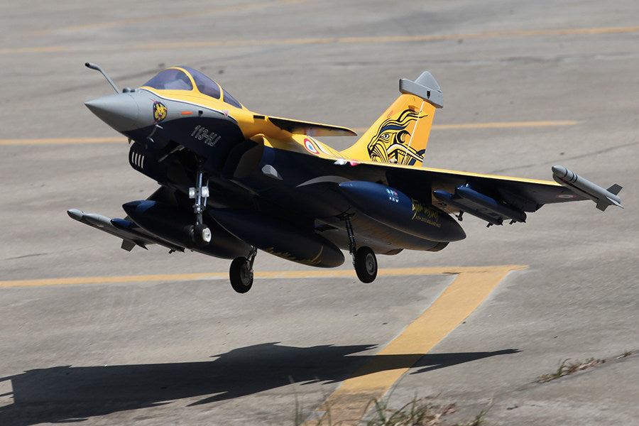 FMS 80mm Rafale jet model with yellow and navy blue livery, retracting landing gear, and detailed markings in flight.